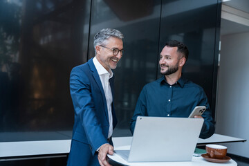 Business manager and colleague discuss work together in modern office
