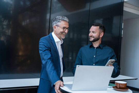 Business manager and colleague discuss work together in modern office