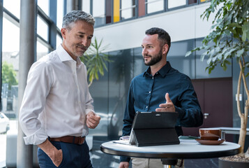 Business managers discussing strategy in modern office with tablet
