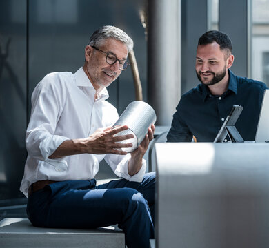 Manager and engineer discussing pipe design in modern office