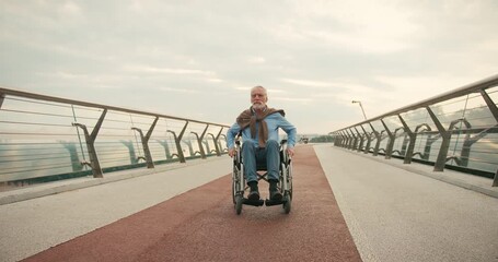 Elderly man sits in wheelchair on bridge walkway gazing intently - Powered by Adobe