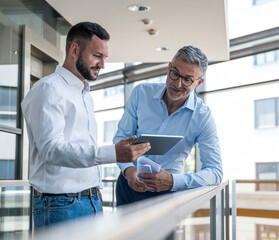 Business professionals discussing work using tablet in office