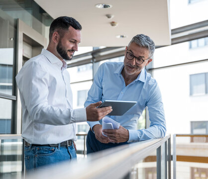 Business professionals discussing work using tablet in office