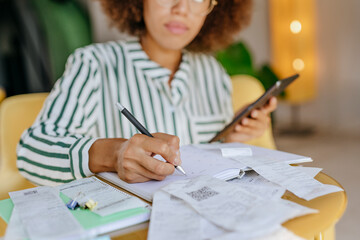 Woman writing budget on book at home
