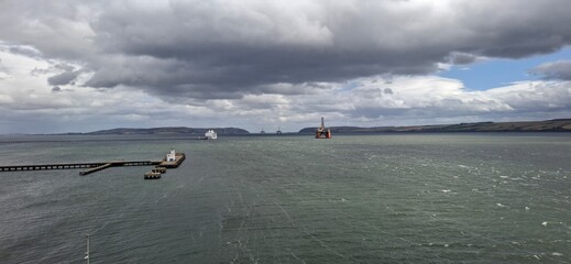 invergordon unitrd kingdom aug 9 2024 Dramatic Seascape with Pier, Ship, and Platforms Under Moody Skies
