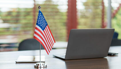 American flag on office desk with laptop in background symbolizing business and government