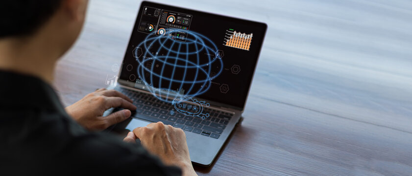 Man using laptop with holographic globe for data analysis, global connection, and technology
