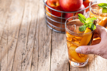 hand holding a glass refreshing peach iced tea in glass with ice cubes. Copy space