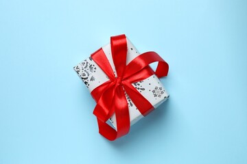 Close up of beautiful Christmas gift with red ribbon on color background, top view, space for text