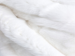 Fototapeta premium A close-up of a white, fluffy fur-like fabric. The fabric has a soft texture with visible strands and folds.