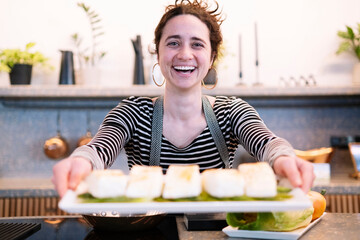 Happy woman presenting food in kitchen indoors