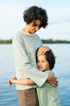 Mother hugging son outdoors showing unconditional love by the water
