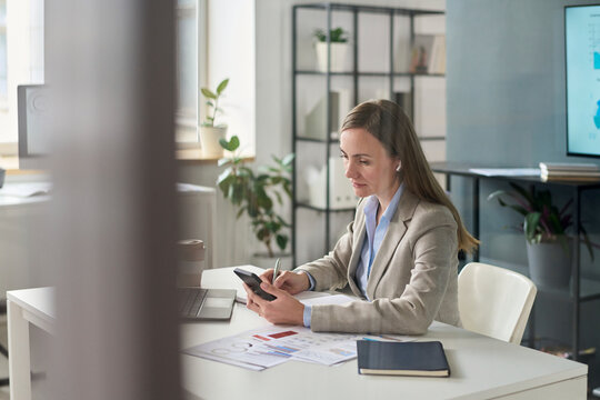 Businesswoman working with smartphone and documents in office