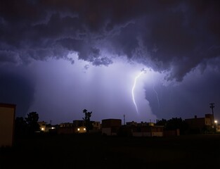 A dramatic thunderstorm illuminates the night sky with a bolt of lightning striking down towards an urban landscape, casting an eerie glow over buildings and silhouetting trees against the dark cloud