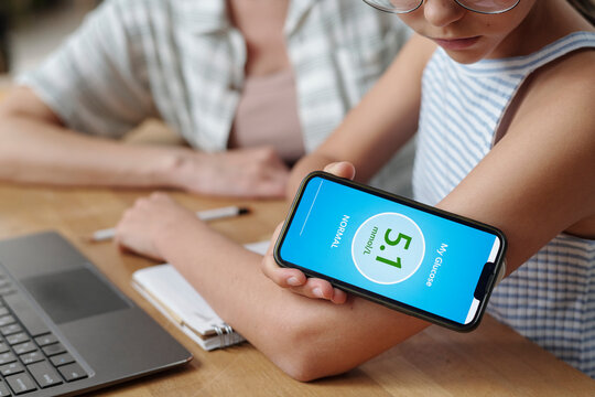 Mother supports daughter checking blood glucose with mobile app at home