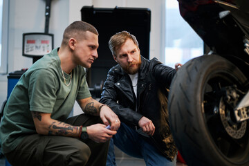 Mechanic and client discussing motorcycle repair in workshop
