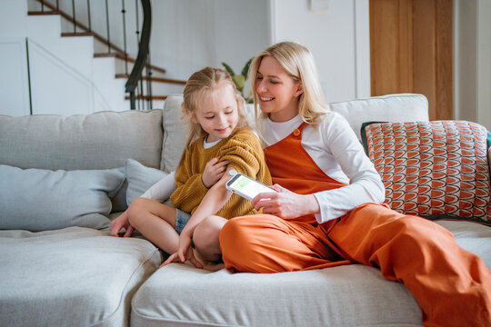 Mother measuring daughter's glucose level at home for diabetes care