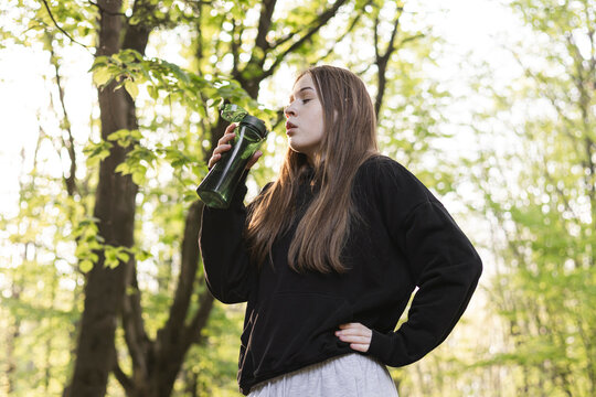 Teenager girl are drinking water from bottle. A girl drinks water after a run.