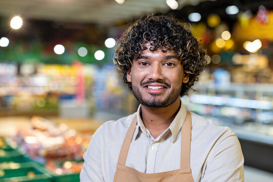 A cheerful grocery store worker confidently posing in an aisle, surrounded by colorful items, symbolizing positive service and teamwork.