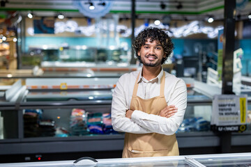 A smiling store employee in uniform, standing confidently in the frozen food section of a supermarket. Showcasing customer service, professionalism, and a clean shopping environment