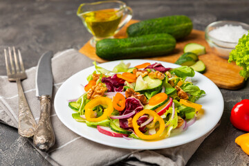 Cucumber salad on a wooden background.Homemade salad with fresh vegetables, cucumber, tomato, sweet pepper and lettuce in a plate.Vegetarian spring salad.Vegetarian diet.Healthy eating.Space for text