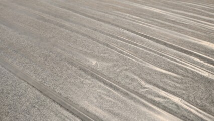 Clear plastic covering the gray carpet. Plastic covering the floor to prevent scratches. Clear plastic to prevent damage. Plastic surface with gray carpet. Texture and background.
