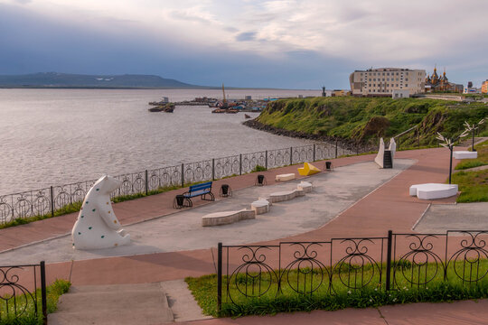 Waterfront promenade in Anadyr, Chukotka, Russia, with sea views, unique benches, sculpture, Orthodox church and modern buildings on Bering Sea.
