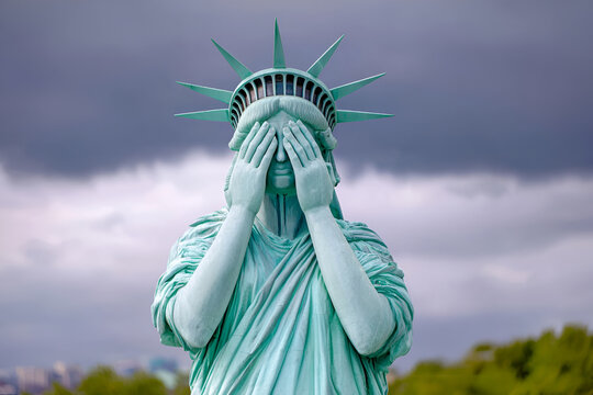 Statue of liberty symbolism with hands covering face against cloudy sky