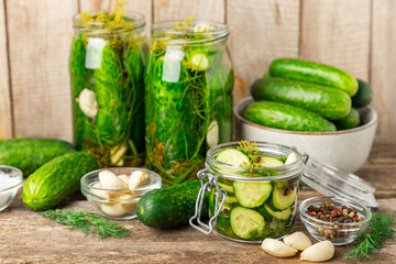 Freshly-salted homemade cucumbers in a jar on a wooden background. pickled cucumbers with dill,garlic and pepper.canned cucumbers.cucumbers and dill.Recipe of homemade preservations.fermented veggies.
