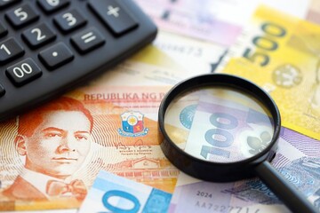 Philippines peso currency money bills and calculator with magnifying glass. The concept of taxation and money count