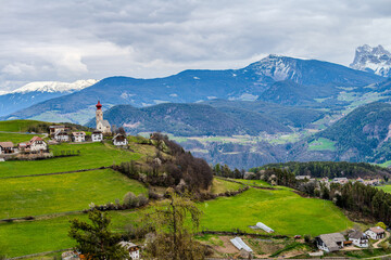Obraz premium Alpine spring view with a distant church seen from near Klobenstein, Ritten, Eisacktal valley, South Tyrol, Italy