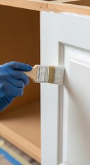 Painting white kitchen cabinet door with brush and gloves