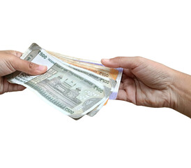A close-up of hands exchanging multiple Indian banknotes, ₹500 and ₹200 notes and ₹100...