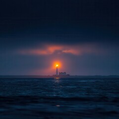 Fototapeta premium Lighthouse beacon shines through a dramatic twilight sky over the water.