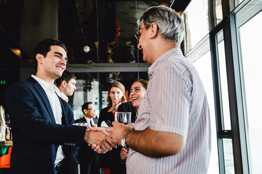 Businessman and colleague exchange a handshake during a casual networking event. Smiling professionals build new connections in a relaxed atmosphere with open conversations and drinks.