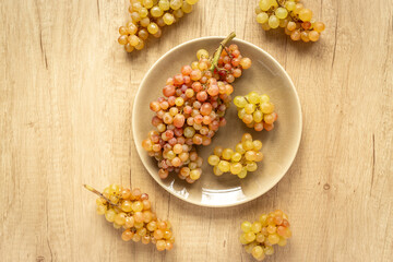 Plate full of ripe yellow grapes, top view