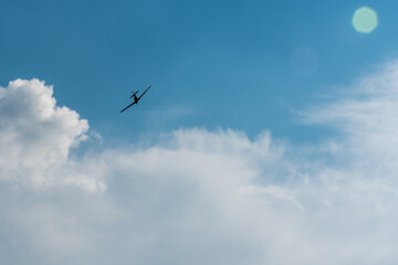Airplane silhouette in turn against bright cloudy sky background