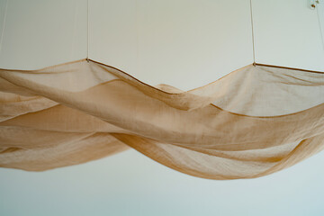 Flowing sheer fabric draped elegantly against a neutral wall creating a soft textured background