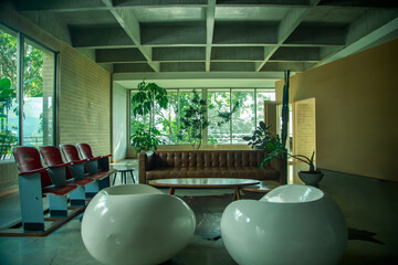 Modern lounge with leather sofa, designer chairs, and large windows overlooking lush greenery