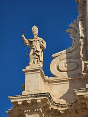 Obraz premium Statue of Bishop on Ornate Building against Blue Sky