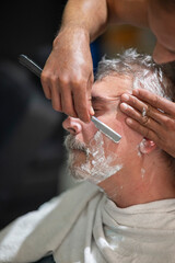 Man receiving a professional straight razor shave with precision and attention in a barbershop