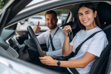 Woman is with instructor in car, driving school concept