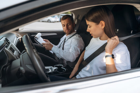 Wearing the safety belt. Woman is with instructor in car, driving school concept
