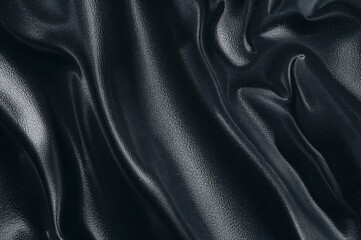 Close up of a dark shiny fabric with soft folds and highlights creating a textured surface look