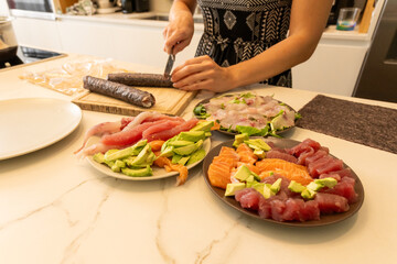 Close-Up of Homemade Sushi Preparation with Fresh Fish, sashimi, and Avocado Slices
