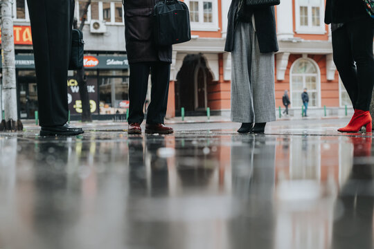 A group of individuals standing outdoors on a wet day in the city, engaging in conversation. Urban environment, teamwork, reflection on the ground adds an artistic touch. - Powered by Adobe