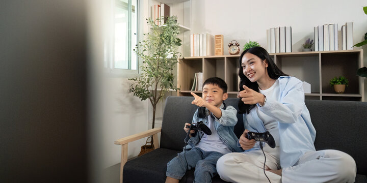 Engaging gaming session. Mother and son excitedly playing video games together.