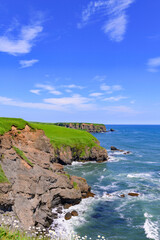 Fototapeta premium 北海道浜中町、琵琶瀬から望む嶮暮帰島（けんぼっきとう）。7月の青空と太平洋の青い海が広がる爽やかな夏の風景。澄み切った空気と美しい水平線が魅力的な景色