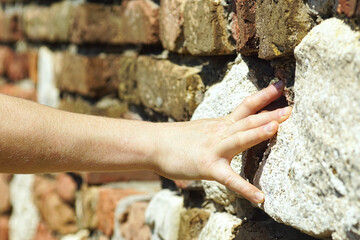 Traveler’s hand on textured masonry wall, symbolizing slow travel, haptic tourism, sensory experiences and authentic cultural immersion. Exploring Belgrade Fortress in Kalemegdan, Serbia by touch. 