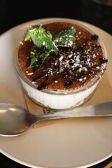 A close-up of an Italian dessert named tiramisu served with cacao, mint on top, in a Parisian restaurant. 
